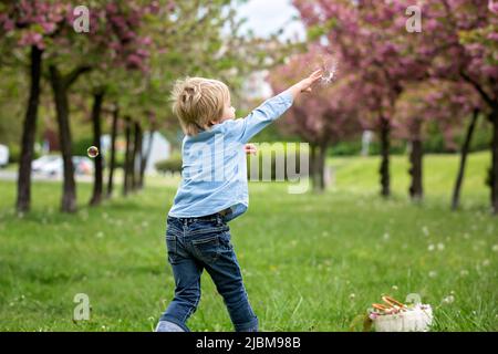 Blonde Kleinkind Kind, niedlichen Jungen in Freizeitkleidung, spielen mit Seifenblasen im Park, laufen glücklich Stockfoto