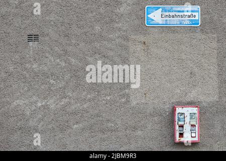 Vintage Gummiball Maschine an einer Wand befestigt und ein deutsches Einwegschild Stockfoto