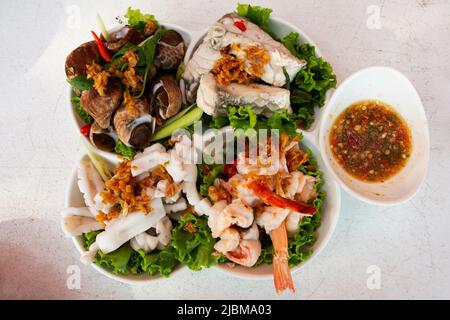 Verschiedene Meeresfrüchte weich gekocht auf Gemüse und moderne Keramikplatte mit würziger saurer Sauce für thailänder Gast Gast essen Getränk auf dem Tisch bei RE serviert Stockfoto