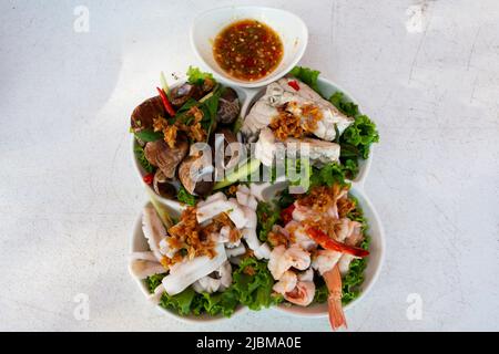 Verschiedene Meeresfrüchte weich gekocht auf Gemüse und moderne Keramikplatte mit würziger saurer Sauce für thailänder Gast Gast essen Getränk auf dem Tisch bei RE serviert Stockfoto