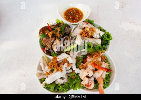 Verschiedene Meeresfrüchte weich gekocht auf Gemüse und moderne Keramikplatte mit würziger saurer Sauce für thailänder Gast Gast essen Getränk auf dem Tisch bei RE serviert Stockfoto