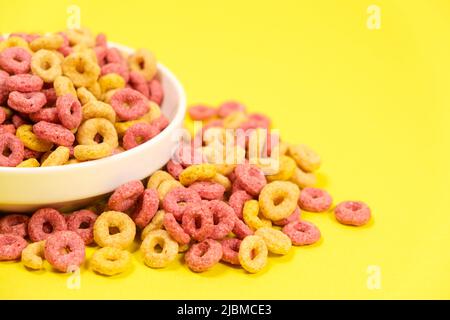 Schnelles Cerealien-Frühstück in Form von Ringen auf einem Teller auf gelbem Hintergrund Stockfoto