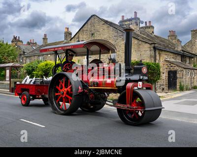 Oldtimer restauriertes schweres altmodisches rotes Dampffahrzeug (schwarzer Kamin, L-Platte, Fahrer) - Burley-in-Wharfedale, West Yorkshire, England, VEREINIGTES KÖNIGREICH. Stockfoto