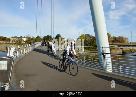 Ein Radfahrer überquert die Lune Millennium Brücke über den Fluss Lune im Stadtzentrum von Lancaster Stockfoto