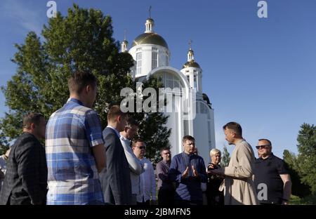 Bucha, Ukraine - 6. Juni 2022 - der erste Vizepräsident des estnischen Riigikogu Hanno Pevkur (C) spricht mit dem Leiter der Kirche des hl. Andreas, dem ersten Apostel Andrii Halavin, Bucha, Region Kiew, Nordukraine. Auf dem Gelände der Kirche des ersten Apostels Andreas wurde eine Massenbestattung von Zivilisten aus Bucha gefunden, die von russischen Invasoren getötet wurden. Dieses Foto kann nicht in der Russischen Föderation verteilt werden. Stockfoto