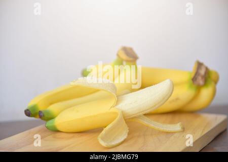 Reife gelbe Bananen auf Holzgrund. Weich ausgewählter Fokus. Draufsicht gelbe Früchte, gelbe Bananen in einem Holztablett. Konzept auf gesunde Lebensmittel-Backgro Stockfoto