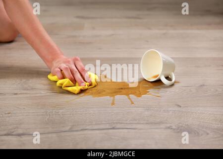 Eine Tasse Kaffee fiel auf Laminat, Kaffee verschüttete sich auf den Boden. Stockfoto