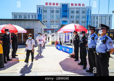 YILI, CHINA - 7. JUNI 2022 - Polizeibeamte stehen am ersten Tag der Aufnahmeprüfung des nationalen Colleges i Wache vor einem Untersuchungszentrum Stockfoto