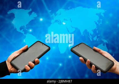 Hände halten Smartphones und Karte der Welt, globales Kommunikationskonzept Stockfoto