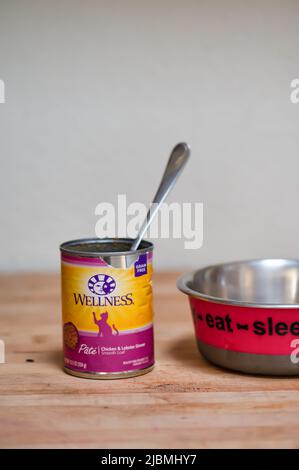 Dose von Wellness Marke Katzenfutter und Metallschale auf Holztheke. Stockfoto