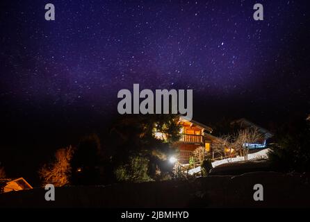 Französisches Dorf mit Holzhäusern, Chalets über Sternen am Himmel Stockfoto