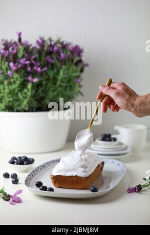 Frau, die den gebumpften Kuchen mit Glasur dekoriert, Nahaufnahme der Hand, die den Kuchen schmückt. Stockfoto