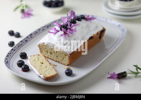 Gebündelter Kuchen mit Verglasung, dekoriert mit frischen Heidelbeerfrüchten und Lavendelblüten. Stockfoto