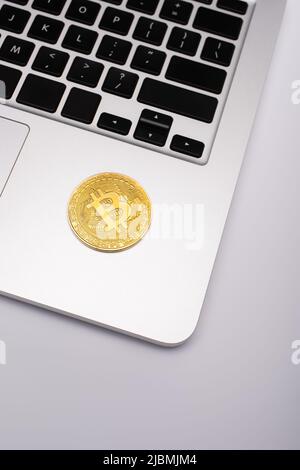KIEW, UKRAINE - 26. APRIL 2022: Draufsicht auf goldenes Bitcoin auf Laptop auf grauem Hintergrund Stockfoto