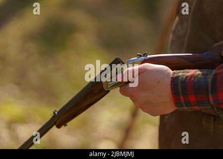 Nahaufnahme eines Jägers lädt die Patrone auf das Gewehr im Wald. Stockfoto