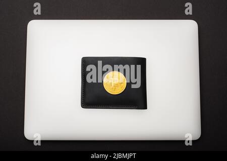 KIEW, UKRAINE - 26. APRIL 2022: Ansicht von oben auf Brieftasche und Laptop isoliert auf Schwarz Stockfoto