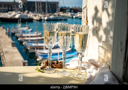 Drei Gläser französischer Champagner Sekt und Blick auf bunte Fischerboote im alten Hafen von Cassis, Provence, Frankreich, Sommerfest in PR Stockfoto