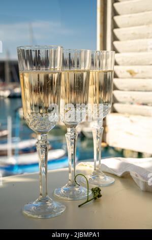 Drei Gläser französischer Champagner Sekt und Blick auf bunte Fischerboote im alten Hafen von Cassis, Provence, Frankreich, Sommerfest in PR Stockfoto