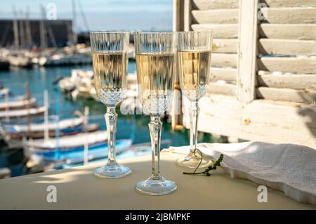 Drei Gläser französischer Champagner Sekt und Blick auf bunte Fischerboote im alten Hafen von Cassis, Provence, Frankreich, Sommerfest in PR Stockfoto