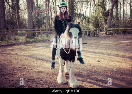 Ein Teenager-Mädchen, das auf einem brüchigen Zigeunerpferd-Pferdepony sitzt und reitet Stockfoto