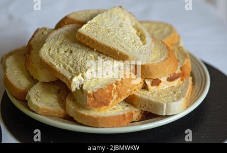 Scheiben gebuttertes Weißbrot stapelten sich auf einem Teller und schossen im Landschaftsformat aus der Nähe Stockfoto