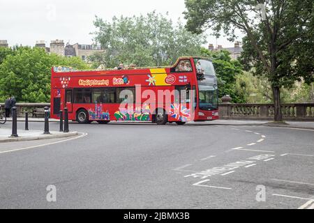 Pulteney Bridge, Bath, Somerset, England, Mai 26. 2022, Ein roter Tourbus wartet auf Touristen Stockfoto