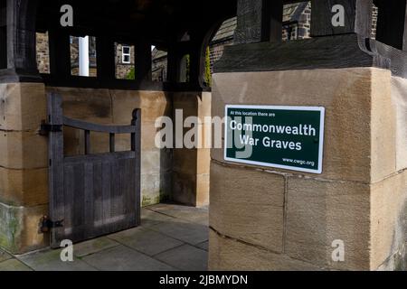 Ein grün-weißes Commonwealth war Graves-Schild am Lychgate der St. John's Church of England, Baildon, Yorkshire. Kriegsgräber befinden sich hier. Stockfoto