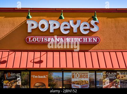 Popeyes Louisiana Kitchen, Außenmarke und Logo in weißen dreidimensionalen Buchstaben über orangefarbener Markise in einem orangefarbenen Strukturgebäude. Stockfoto