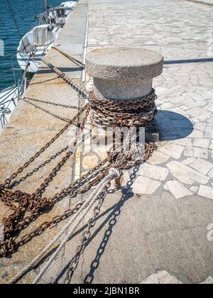 Ein Betonpfand an einem Steinkayside mit Ketten und Seilen an einem sonnigen Tag. Stockfoto