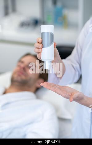 Kosmetologin mit einer Flasche mit Creme Stockfoto