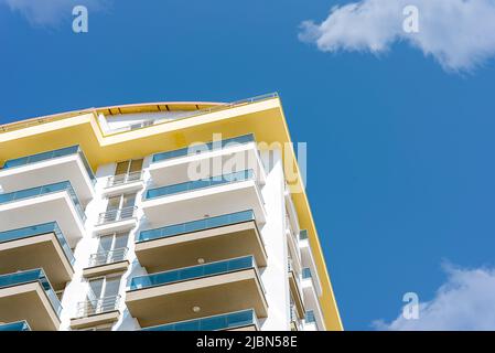 Gelbe und blaue moderne, belüftete Fassade mit Fenstern. Fragment eines neuen Wohn- oder Geschäftsgebäudes. Teil der Stadt Immobilien. Stockfoto