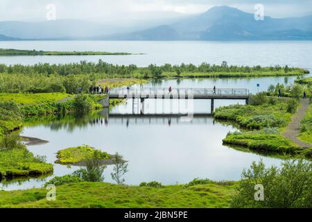 Touristen auf einer Brücke im Thingvellir Nationalpark im Sommer, Island Stockfoto