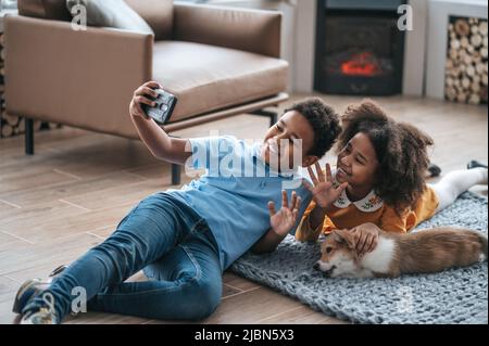 Ein Junge in blauem T-Shirt, der Selfie mit seiner Schwester und einem Hund macht Stockfoto