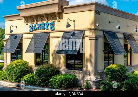 Zaxby's Restaurant Außenfassade Marke und Logo Signage in Pulverblau auf einem gelb beigen Gebäude mit Fensterblenden an einem hellen sonnigen Tag. Stockfoto