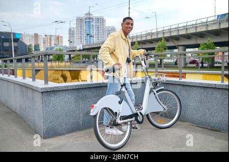 Typ steht mit Fahrrad und schaut auf die Kamera Stockfoto