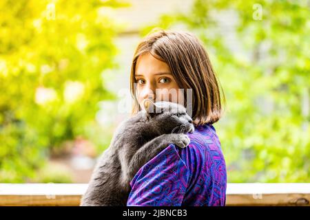 Junge attraktive Mädchen hält eine russische blaue Katze mit sonnigen Sommer Hintergrund Stockfoto