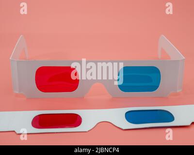Rote und blaue Papiergläser für 3D Filme und Bilder. Isoliert auf einem rosa Hintergrund. Stockfoto