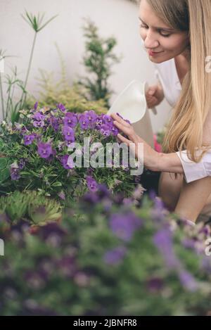 Frau, die Blumen auf dem Dachgarten wässert Stockfoto