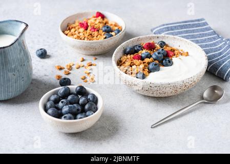Müslischale mit Blaubeeren und getrockneten Himbeeren auf grauem Betontisch-Hintergrund, Nahaufnahme Stockfoto