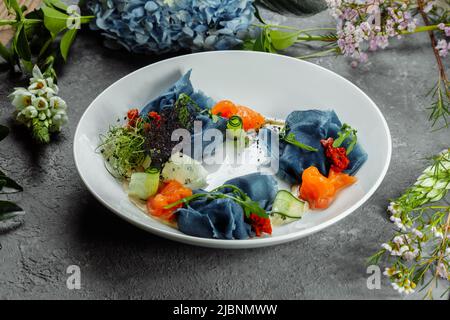 Ein Stapel Pfannkuchen mit gesalzenem Lachs auf einem Teller. Blaue Pfannkuchen mit Lachs. Nützliches Frühstück Stockfoto