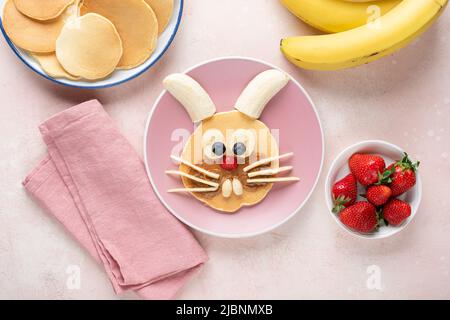 Food Art Frühstück Pfannkuchen in Form von Kaninchen oder Hase für Kinder, Baby, auf einem rosa Hintergrund, Draufsicht Stockfoto