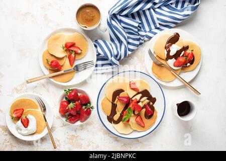 Familienfrühstück Pfannkuchen mit Erdbeeren und Sahnesauce und Schokoladensauce, Draufsicht flach Lay Zusammensetzung Stockfoto
