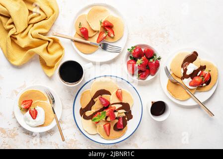 Pfannkuchen mit Schlagsahne, Erdbeeren und Schokoladensauce. Draufsicht. Süße Pfannkuchen zum Familienfrühstück Stockfoto