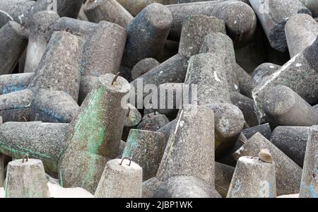 Betonbruchwässer aus Tetrapodenblöcken. Wellenbrecher am Strand und in den Dünen. Betonblöcke am Strand. Stockfoto