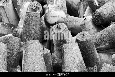 Betonbruchwässer aus Tetrapodenblöcken. Wellenbrecher am Strand und in den Dünen. Betonblöcke am Strand. Stockfoto