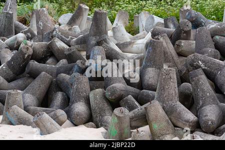 Betonbruchwässer aus Tetrapodenblöcken. Wellenbrecher am Strand und in den Dünen. Betonblöcke am Strand. Stockfoto