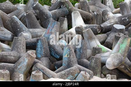 Betonbruchwässer aus Tetrapodenblöcken. Wellenbrecher am Strand und in den Dünen. Betonblöcke am Strand. Stockfoto