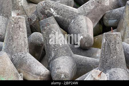 Betonbruchwässer aus Tetrapodenblöcken. Wellenbrecher am Strand und in den Dünen. Betonblöcke am Strand. Stockfoto