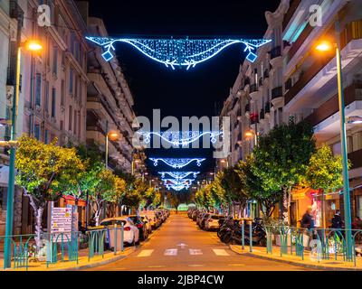 Menton, Frankreich - 6. Dezember 2021: Eine beleuchtete und weihnachtliche Straße in Menton, Frankreich, bei Nacht. Stockfoto