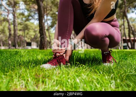 Junge Brünette Frau trägt sportliche Kleidung im Stadtpark, im Freien leiden an einer Knöchelverletzung beim Training und Laufen. Gesundheit und Sport Stockfoto